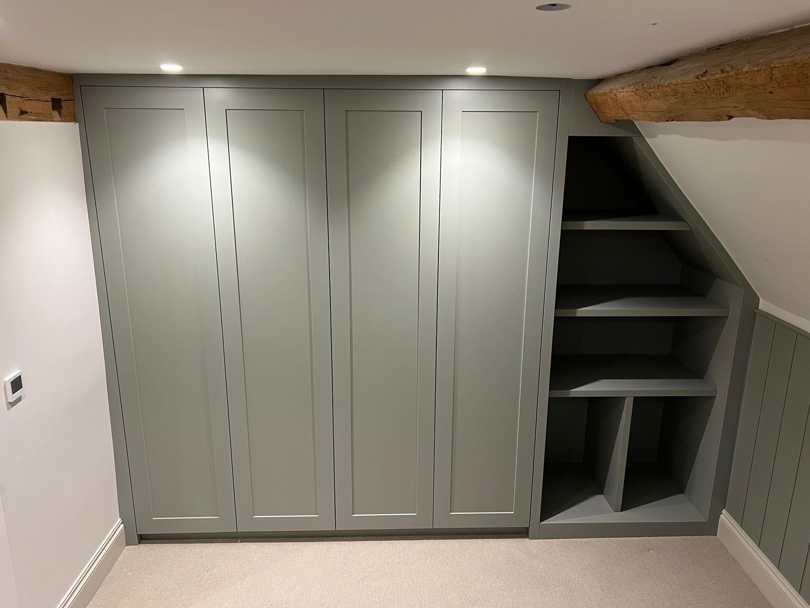 Fitted sage green wardrobes built into a sloping eaves bedroom with open shelving, Wallingford