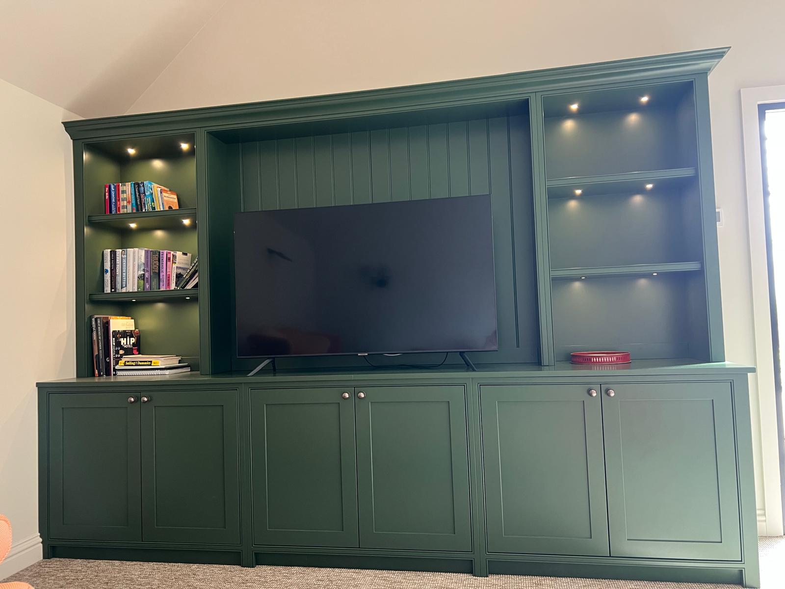 Bespoke green media wall with lit display shelving, panelled back and TV recess