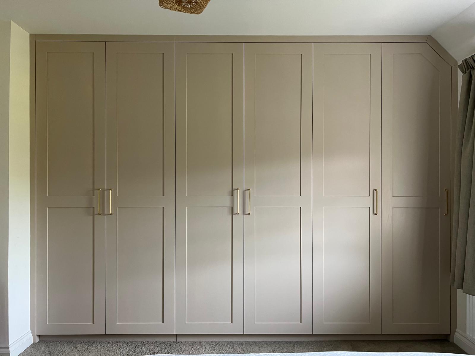 Fitted bedroom wardrobes in cream running into a sloping ceiling corner