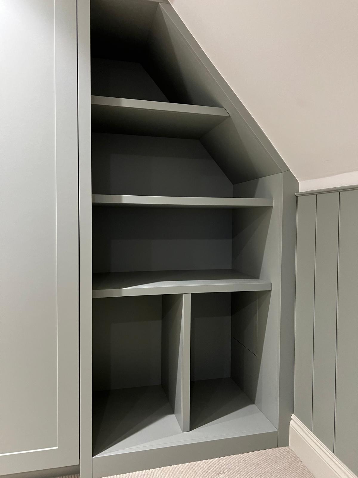 Bespoke understairs storage with stepped shelving built into the stair void