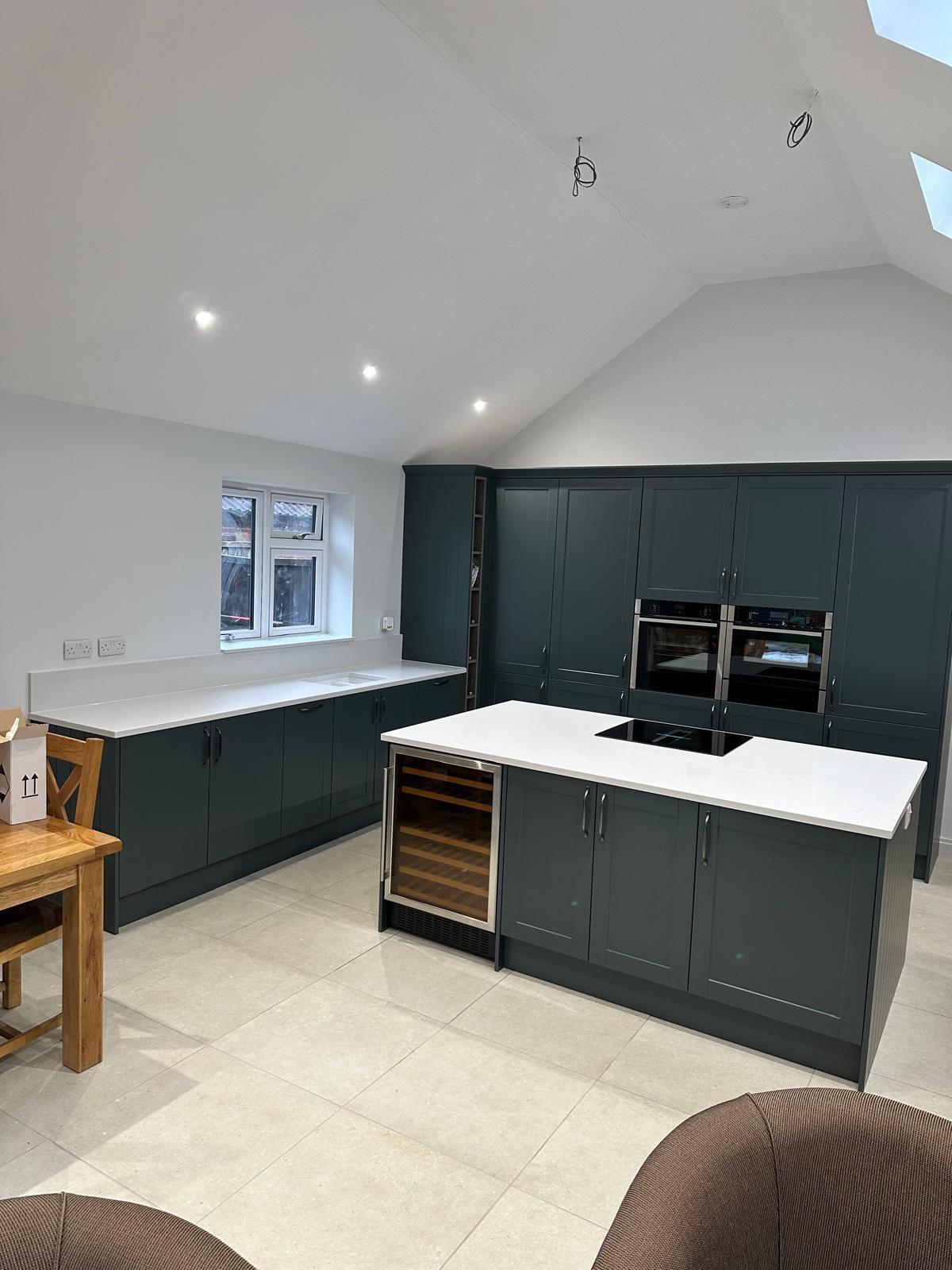 Dark green shaker kitchen fitted by CZ Bespoke Carpentry with island and integrated appliances