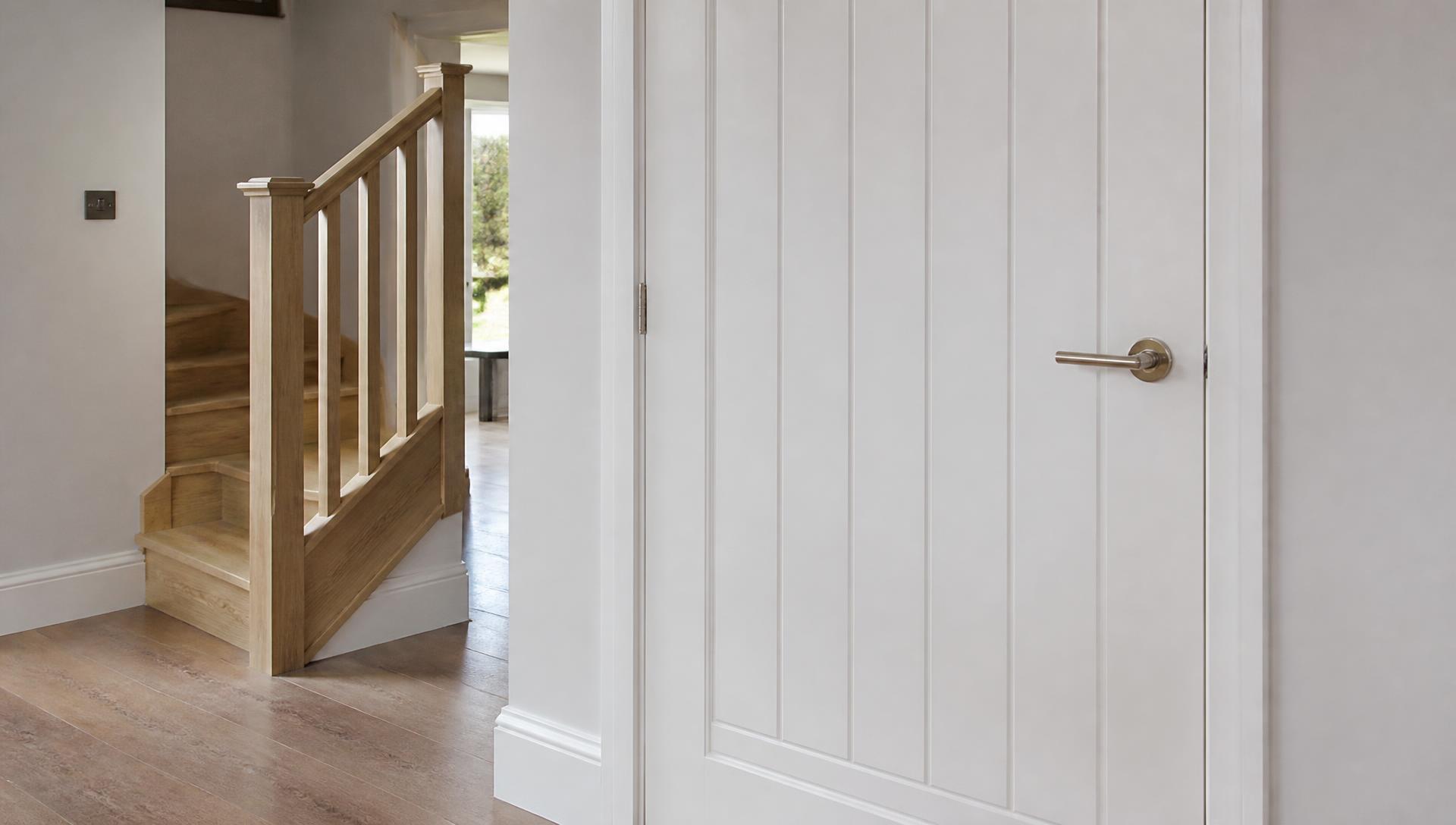 Second fix carpentry detail with a fitted painted door, architrave, skirting and oak staircase