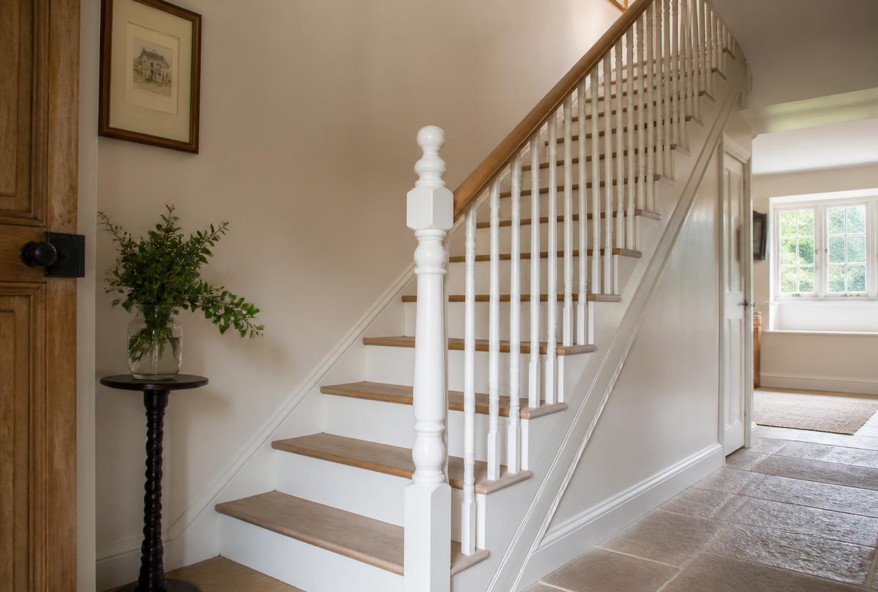 Bespoke painted staircase with oak treads, turned newel post and slim spindles in a country hallway